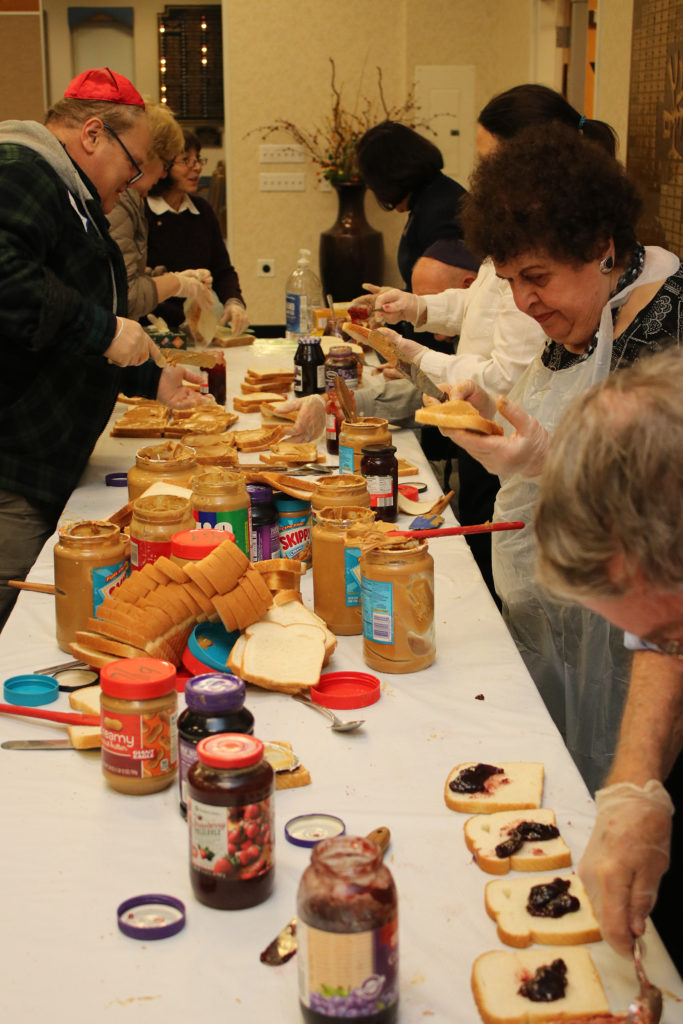 Several Temple Israel Ner Tamid congregants prepare peanut butter and jelly sandwiches.