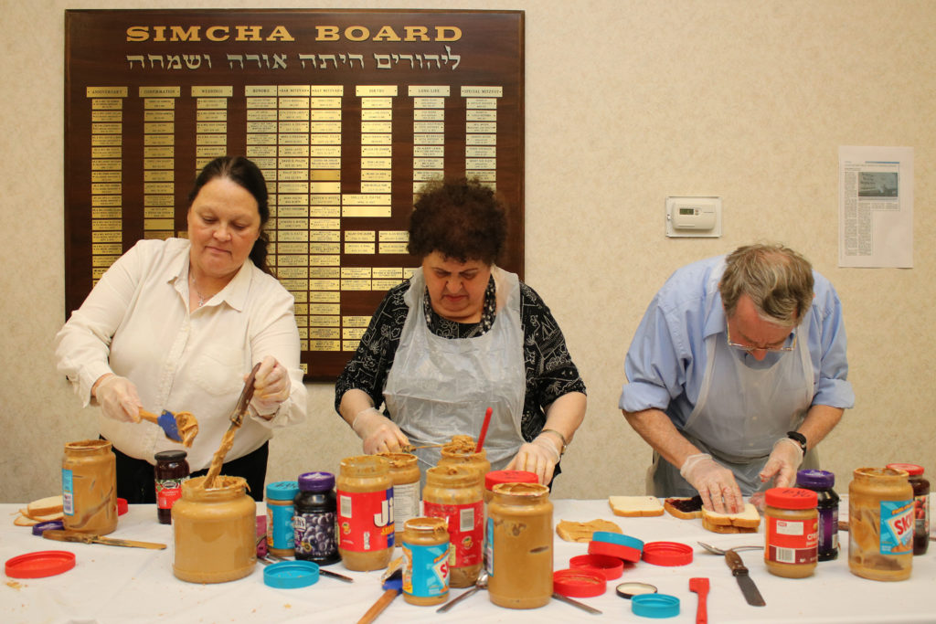 Congregants Terri Greer, Audrey Heller and Joe Leve prepare peanut butter and jelly sandwiches.